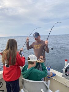 Dad help his daughter and son while fishing and the each have a fish on the line at the same time