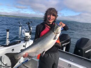 young teenage boy holding a large king salmon while on a lake Michigan charter fishing trip