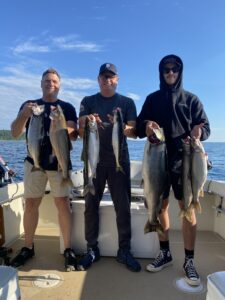 three-men-holding two-or-three-fish-each-of-large-king-salmon-and-lake-trout-from-traverse-city-fishing-on-grand-traverse-bay-aboard-charter-boat