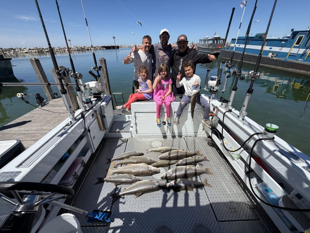 Family on a Traverse City fishing charter showing off their Lake Trout catches