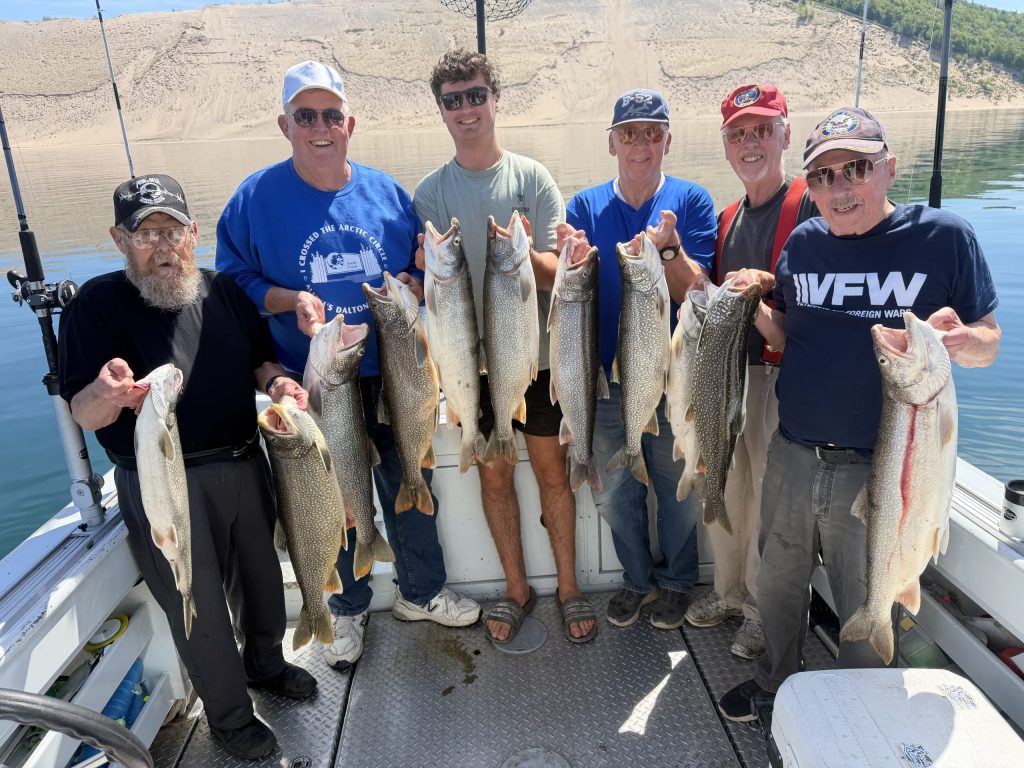 Traverse city fishing charter group holding up their best catches of the day out of Grand Traverse Bay