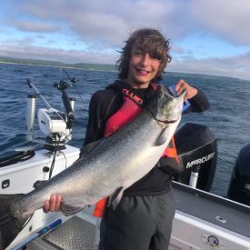 young teenage boy holding a large king salmon while on a lake Michigan charter fishing trip